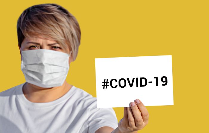 Woman in face mask hold blank with inscription COVID-19. World Health Organization WHO introduced new official name for Coronavirus disease named COVID-19