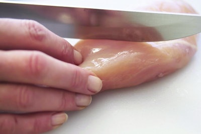 Women Hand sliced .?..??.?..??fresh chicken breast with a knife on the white desk