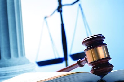 A gavel rests on top of an open law book with a justice scale and a Greek column in the background.