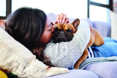 Shot of a young woman relaxing with her dog at home