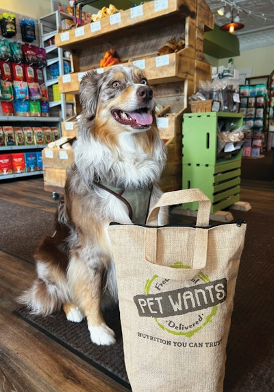 Pet Wants’ model is to provide multiple ways for its customers to get their food, whether it’s from a physical retail location, delivered to their home or purchased online. (Pictured: Australian Shepherd Elliot Januszki with his Pet Wants haul.)