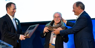Jarod Morrison, left, chief financial officer for Farbest Foods, and outgoing USPOULTRY chair, presents the Workhorse of the Year plaque to Tom Hensley, president of Fieldale Farms and past USPOULTRY chair, while he is being “collared” by Greg Hinton, vice president of sales at Rose Acre Farms and past USPOULTRY chair.