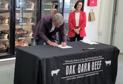Nebraska Gov. Jim Pillen signs an executive order that restricts state agencies and contractors from obtaining lab-grown meat, as Nebraska Department of Agriculture Director Sherry Vinton looks on.