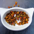 Colorful pet food kibble in a white cat-shaped bowl on a textured blue surface