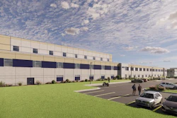Modern industrial warehouse facility with multi-story design, parking area, and landscaped grounds under cloudy sky