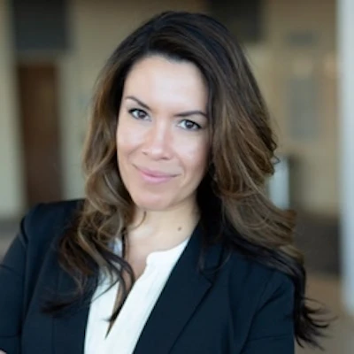 Professional headshot of a woman in business attire with dark blazer and white blouse