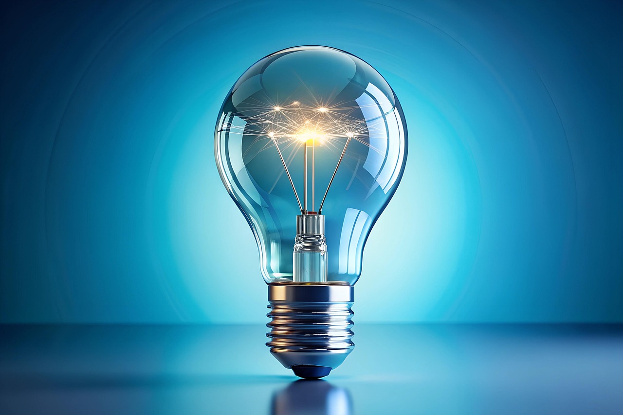 Glowing incandescent light bulb with illuminated filament against blue gradient background