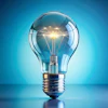 Glowing incandescent light bulb with illuminated filament against blue gradient background