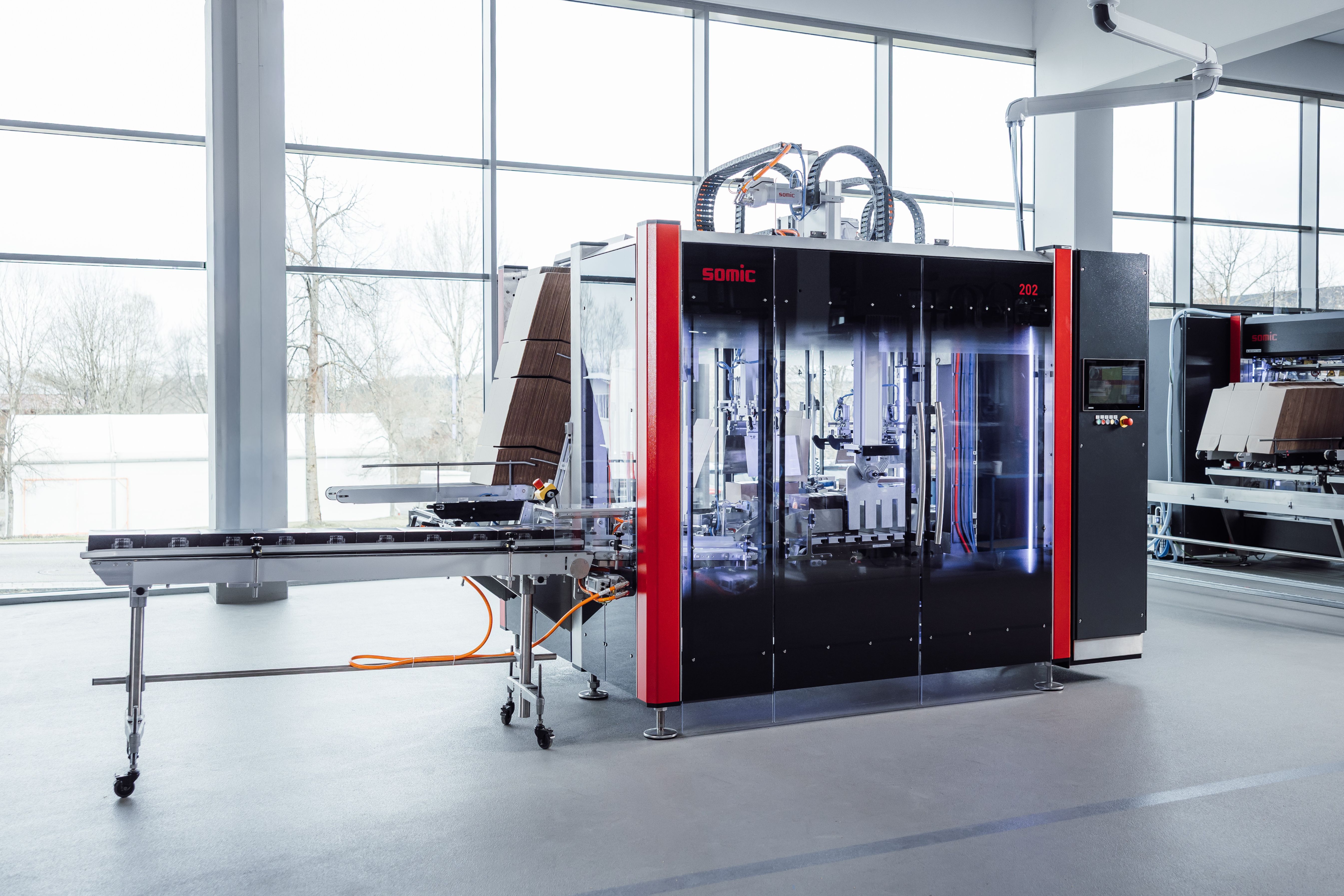 SORMIC industrial automated manufacturing machine with red and black frame in modern facility with large windows