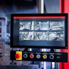 Surveillance monitoring system with display screen showing aerial city camera feeds and control panel with colored buttons