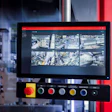Surveillance monitoring system with display screen showing aerial city camera feeds and control panel with colored buttons