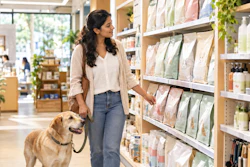 Woman shopping with golden retriever in natural products store aisle