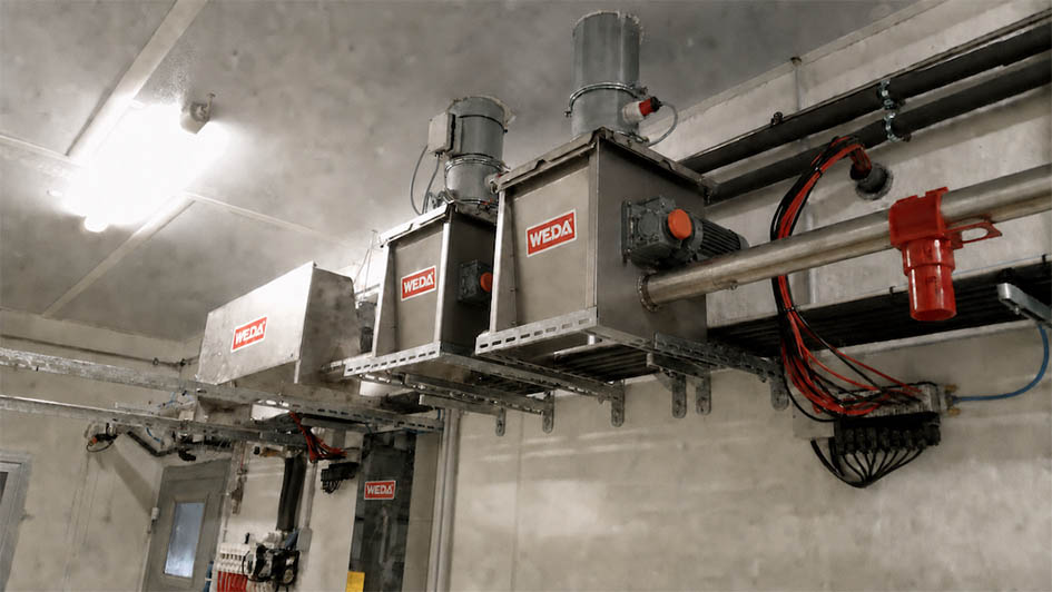 Industrial WEDA vacuum lifting systems mounted on ceiling rails in warehouse facility