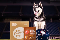 Husky dog sitting with The Farmer's Dog pet food packaging and crunchy biscuit treats on grass