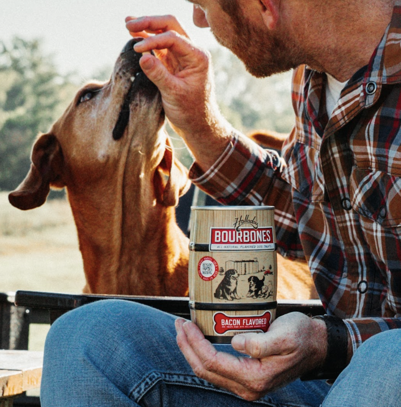 Man feeding dog a Hollings Bourbones bacon-flavored treat outdoors