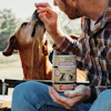 Man feeding dog a Hollings Bourbones bacon-flavored treat outdoors