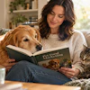 Woman reading Pet Food Marketing book on couch with golden retriever and tabby cat in bright living room