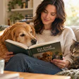 Woman reading Pet Food Marketing book on couch with golden retriever and tabby cat in bright living room