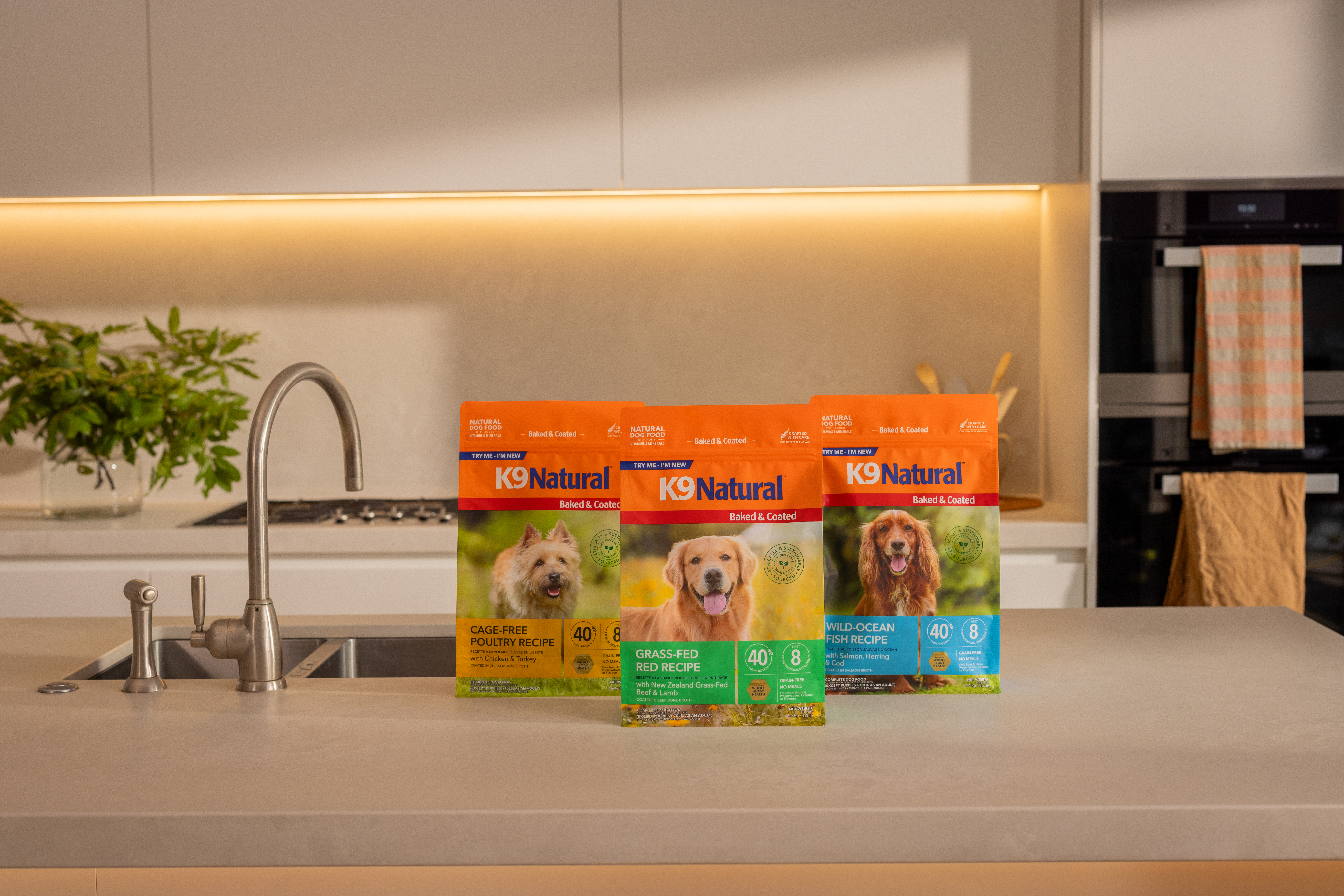 K9 Natural dog food packages displayed on modern kitchen counter with faucet and plants