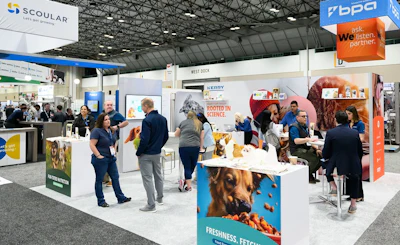 Trade show exhibition floor with multiple vendor booths displaying pet food and animal care products
