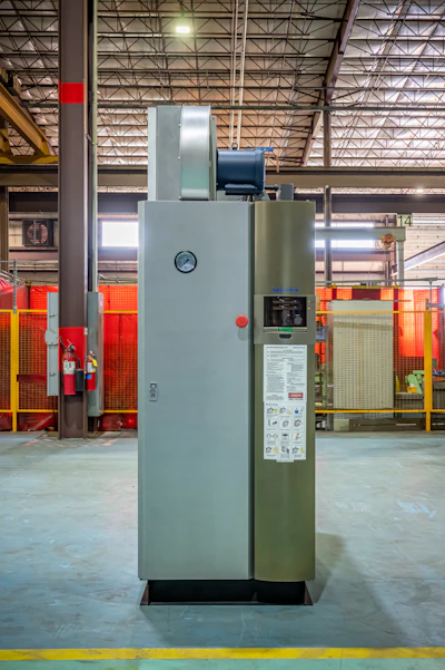 Industrial air compressor system in factory warehouse with red safety barriers and metal framework ceiling