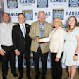 Seven professionals posing with award at Kansas Commerce awards event backdrop