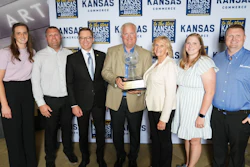 Seven professionals posing with award at Kansas Commerce awards event backdrop