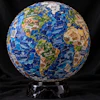 Decorative globe crafted from pet food brand packaging featuring blue oceans and green continents on a black marble stand