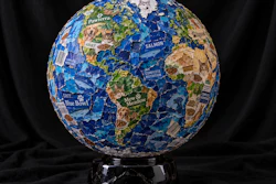 Decorative globe crafted from pet food brand packaging featuring blue oceans and green continents on a black marble stand