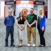 Four Petco employees standing together in store entrance with welcome signage and pet food branding visible behind them