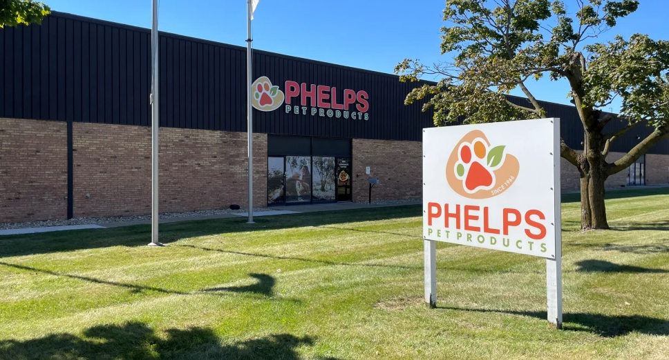 Phelps Pet Products storefront with white ground sign featuring orange paw print logo and building signage