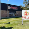 Phelps Pet Products storefront with white ground sign featuring orange paw print logo and building signage