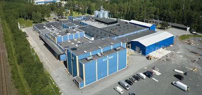Aerial view of blue and white industrial storage facility with multiple units, parking area, and surrounding forest