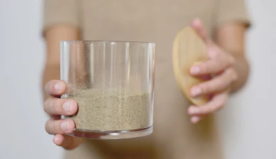 Person holding glass of sand and potato demonstrating food preparation or nutritional comparison