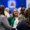 Professional woman in green blazer networking with colleagues at a corporate event or conference