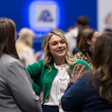 Professional woman in green blazer networking with colleagues at a corporate event or conference