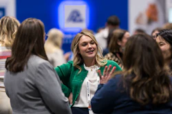 Professional woman in green blazer networking with colleagues at a corporate event or conference