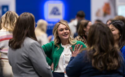 Professional woman in green blazer networking with colleagues at a corporate event or conference